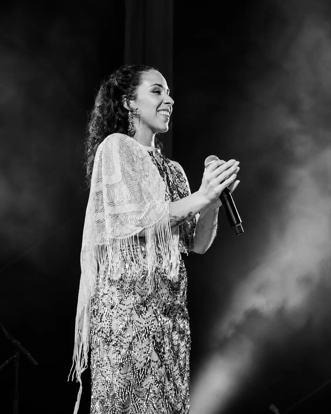 Inês Almeida a cantar em palco, de xaile, num retrato a preto e branco